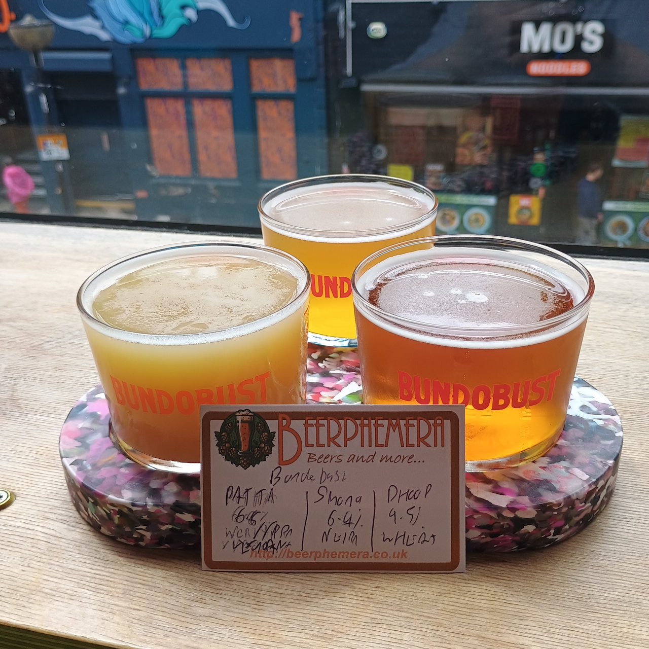 A flight of Bundobust beers, including PATTA (6.8% West Coast Rye IPA in collaboration with Verdant Brewing Co.), DHOOP(4.5% Wheat Beer), and Shona (6.4% New England IPA). Taken at Bundobust, Liverpool on 3/6/26 because I really like the look of the Bundobust flight board.