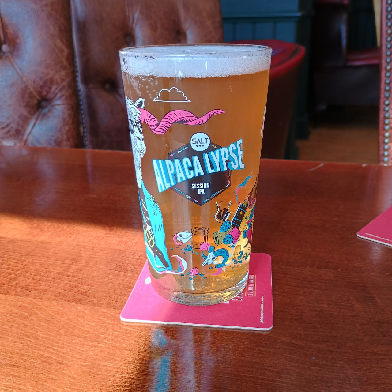 A full glass of Alpacalypse, showing the logo and various post-apocalyptic debris.